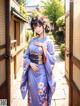 A woman in a blue kimono standing in front of a door.