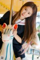 A young woman holding a toy horse on a carousel.