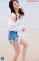 A woman standing on a beach next to the ocean.