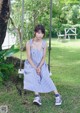 A woman sitting on a swing in a blue and white striped dress.