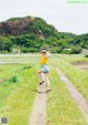 A woman in a yellow shirt and blue shorts running down a dirt road.