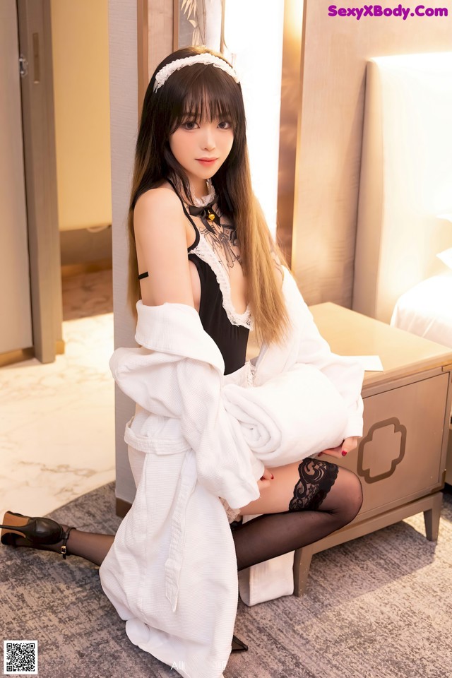 A woman in a white robe sitting on a bed.