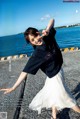 A woman in a black shirt and white skirt posing for a magazine.