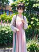 A woman in a pink and blue dress standing in a garden.