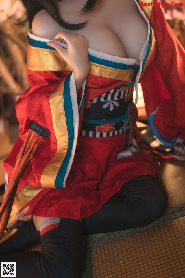 A woman in a red and blue kimono sitting on a couch.