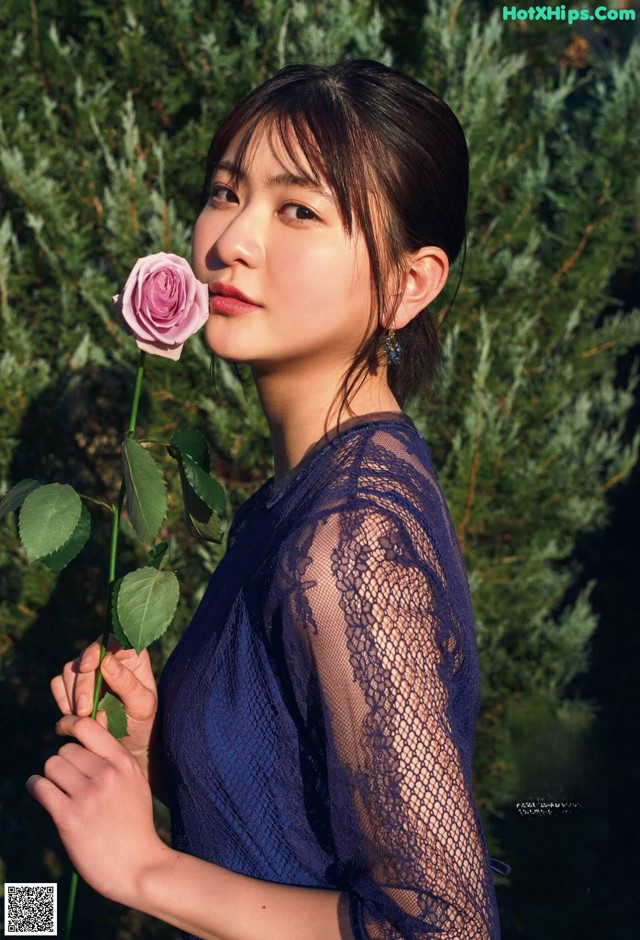 A woman in a blue dress holding a pink rose.