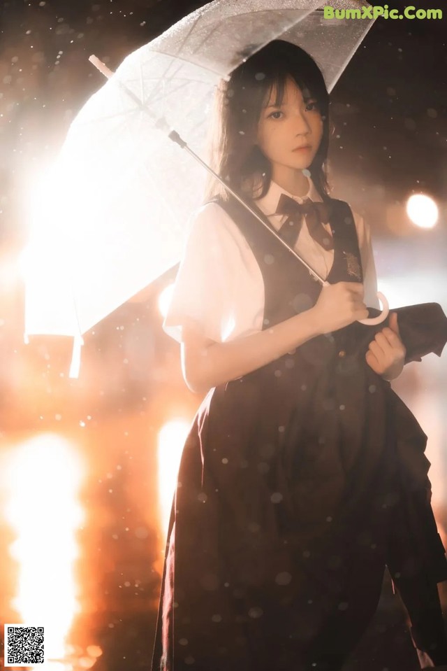 A woman in a black dress holding an umbrella.