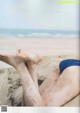 A person laying on a beach with their feet in the sand.